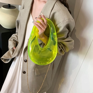 Neon lime transparent acrylic box clutch with gold chain strap held by model