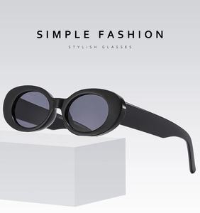 Detail of trendy oval black sunglasses with glossy frames on a white platform