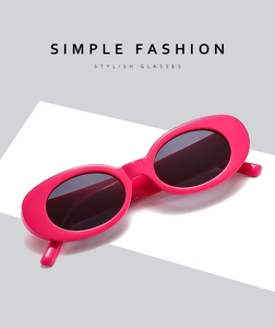 Detail view of oval magenta sunglasses with dark lenses on a minimalist pedestal