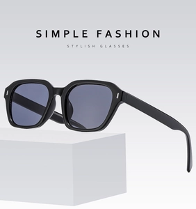 Détail de lunettes de soleil noires à monture épaisse avec accents métalliques argentés