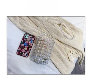 Detail of clear acrylic pearl beaded mini bucket bag showing size comparison with a phone