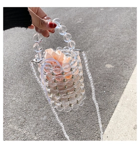 Macro detail of handmade clear acrylic bead bucket bag with a pink drawstring satin lining