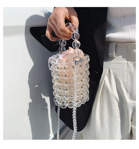 Detailed close-up of a clear acrylic pearl bucket bag with pink satin drawstring liner