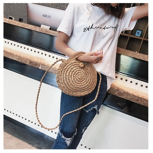 Detail of a handmade round straw beach bag with a woven strap and spherical closure