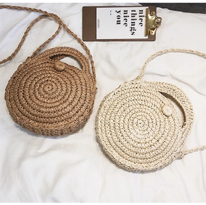 Detail of round handmade woven straw bags in khaki and cream with dual handles
