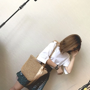 Detail of hand-woven straw tote bag with elegant beige silk ribbon bow decoration