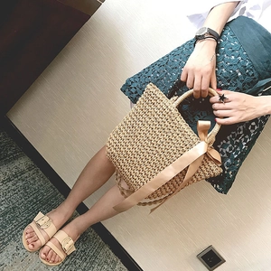 Aerial view of a handmade woven straw handbag with a silk scarf and matching beach sandals