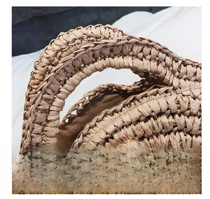 Detail showing the sturdy woven handle and brown fabric lining of the straw beach handbag
