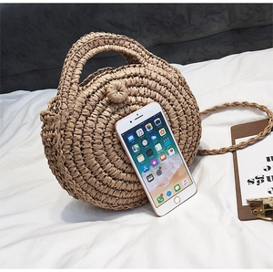 Straw beach bag detail showing woven texture and circular design next to a mobile phone