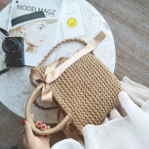 Detailed top view of handmade straw tote bag with satin ribbon bow and woven ring handle