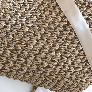 Macro detail of the woven texture and champagne satin ribbon on this beach bag