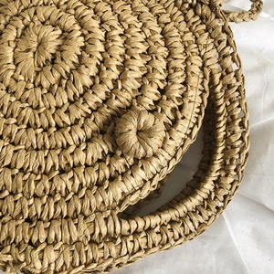 Handcrafted round straw beach bag with natural woven texture and bohemian vacation style