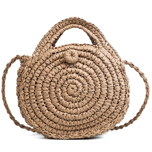 Handwoven round straw beach bag with circular handles and a slender crossbody strap