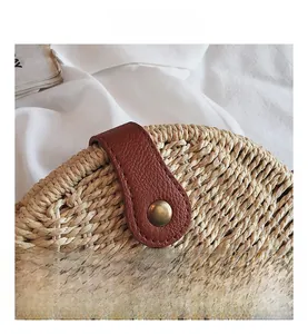 Detail des Papierstroh-Taschenverschlusses mit braunem Lederband und Vintage-Metallschließe