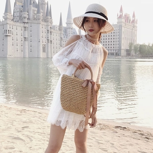 Handwoven straw beach bag with wooden handles and a pink bow tassel for summer vacation