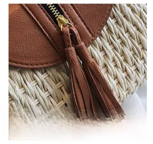 Vue détaillée du sac en paille avec rabat en cuir marron et breloques à pompons