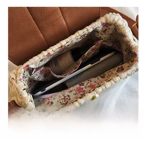 Vue intérieure du sac en paille avec doublure florale et espace pour cosmétiques et mobile