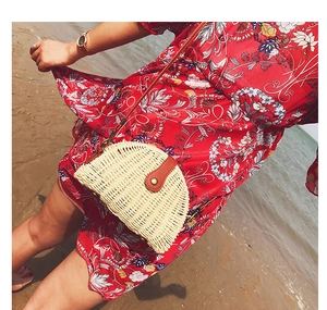 Detail der beigen Strohtasche mit braunem Lederverschluss vor einem Strandhintergrund