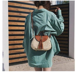 Photo en extérieur d'un sac bandoulière en paille tissée avec détails en cuir marron