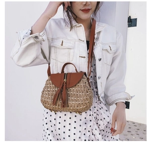 Sac en paille avec rabat en cuir et pompon porté avec une veste en jean blanche