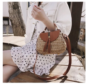 Détail du sac de plage en paille avec rabat en cuir marron et pendentif à pompon long