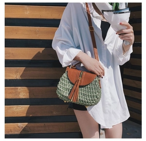 Détail du sac de paille vert avec rabat en cuir marron et long gland élégant