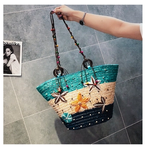Detail of tricolor woven straw beach bag with 3D floral accents and colorful beads