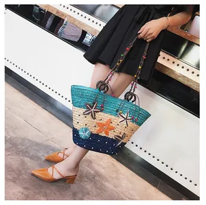 Detail of color-block straw tote bag featuring 3D floral and starfish decorations