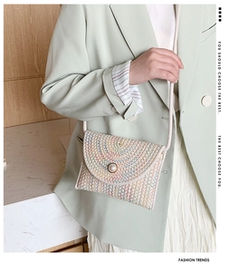 Détail d'un sac bandoulière en paille tissée colorée avec boucle en perle sur veste