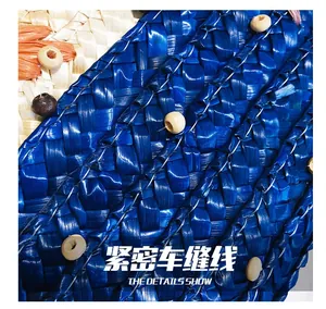 Detail of blue straw woven bag with circular wood beads and reinforced white stitching