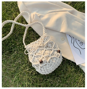 Dettaglio borsa a secchiello in cotone bianco intrecciato con coulisse e perline in legno