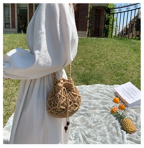 Dettaglio della borsa a secchiello in paglia beige tessuta a mano con perle di legno