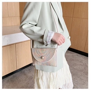 Détail du sac à bandoulière en paille avec motifs colorés et fermoir perle