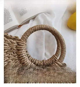 Gros plan du sac en paille tressée montrant la poignée ronde et la texture des fibres