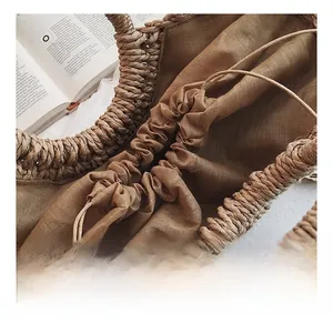 Détail du sac en paille tressé à la main avec fermeture à cordon et doublure en lin