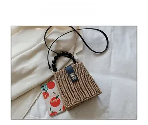 Detail of straw woven bag with black beaded handle and phone for size comparison