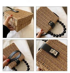 Detail view of woven straw box bag with black bead handle and silver metal turn-lock