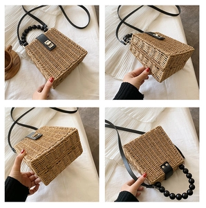 Detail view of woven straw handbag featuring black beaded handle and metallic lock closure