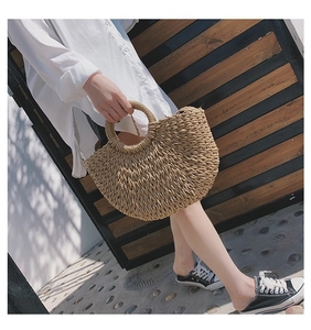 Détail d'un sac en paille fait main avec forme semi-circulaire et poignées tressées