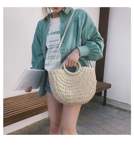 Détail du sac à main en paille tressée beige avec poignées rondes et bandoulière pour la plage