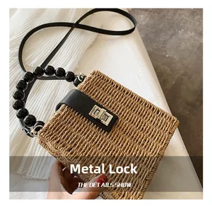 Close-up of the woven straw texture with a black leather flap and silver metal turn-lock