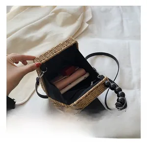 Interior view of square straw bag showing capacity for phone, wallet and lipstick