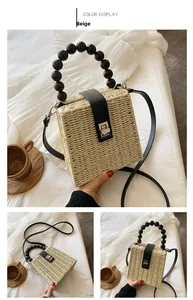 Detail of beige straw box bag with black beaded handle and silver twist lock closure