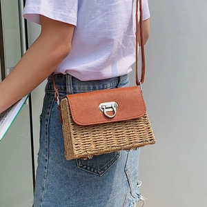 Détail du sac à bandoulière en paille tressée avec rabat en cuir brun et boucle à anneau argenté