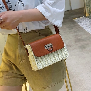 Détail du sac bandoulière en paille avec rabat en cuir marron et fermoir rotatif