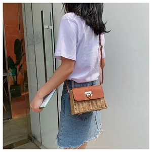 Sac bandoulière en paille avec rabat en cuir marron porté par un mannequin