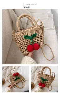 Detail of straw bag in khaki with handmade crochet cherry decor and shoulder strap