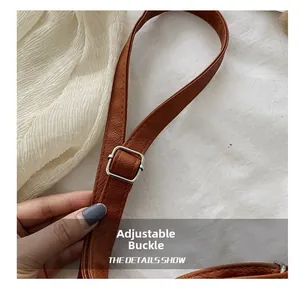 Détail de la bandoulière en cuir marron avec boucle de réglage en métal argenté brillant