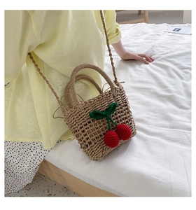 Detailed view of woven straw bag with handmade 3D cherry accents and shoulder strap
