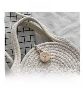 Detail of round straw bag showing handmade weave and wooden button with tree engraving
